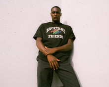 Load image into Gallery viewer, Oversized College Logo T-Shirt on body, portrait of man posing, leaning against a wall